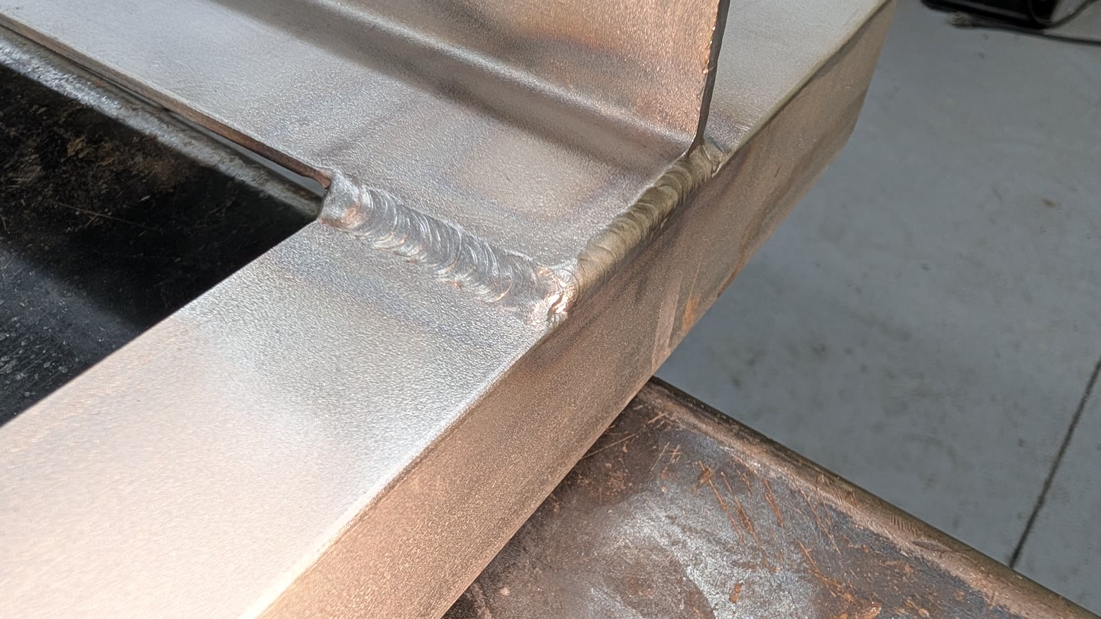 Close-up of a clean aluminum weld bead joining two plates.