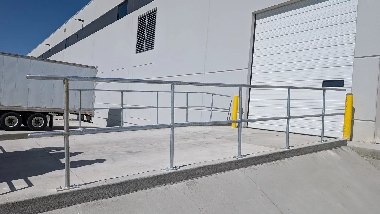Galvanized pipe railing installed around a warehouse loading dock.