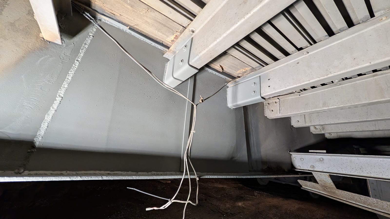 Underside of a trailer with fresh welds and reinforcement along the cross members.